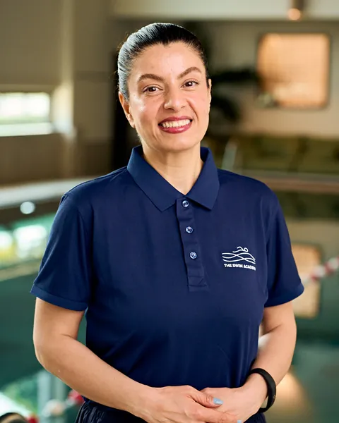 Rose, TSA coach, smiling beside the pool in a navy TSA polo